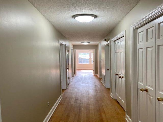 hall featuring a textured ceiling and light hardwood / wood-style flooring