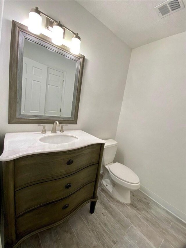 bathroom featuring toilet, oversized vanity, and wood-type flooring