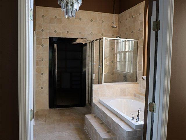 bathroom with a notable chandelier, tile floors, tile walls, and separate shower and tub