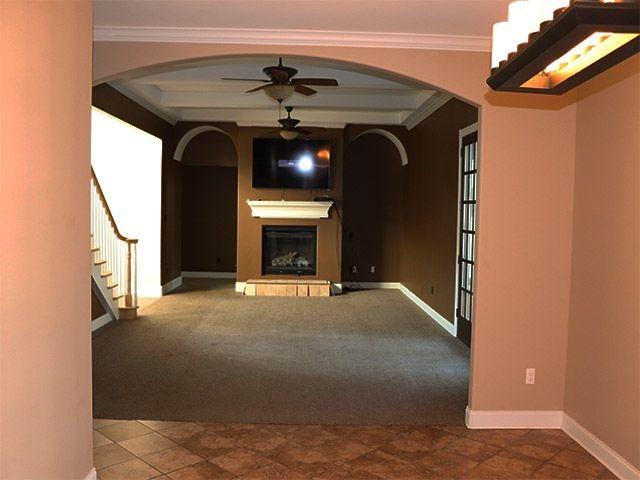 unfurnished living room with beamed ceiling, carpet, ceiling fan, and ornamental molding