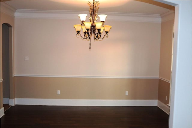 spare room with an inviting chandelier, ornamental molding, and dark hardwood / wood-style floors