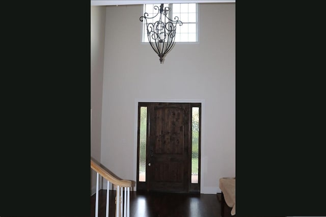 foyer featuring plenty of natural light, an inviting chandelier, and dark hardwood / wood-style flooring