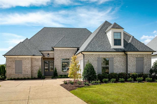 french provincial home with a front yard and french doors