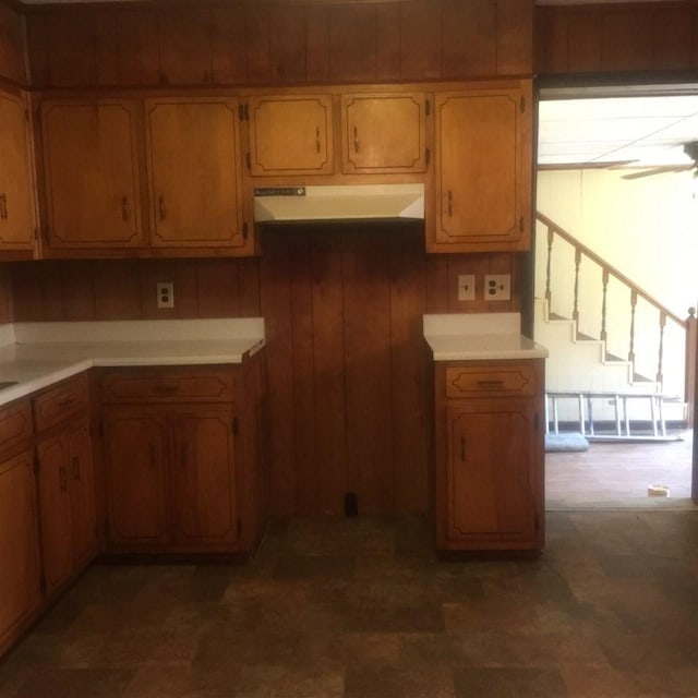 kitchen with wood walls, ceiling fan, and dark tile flooring