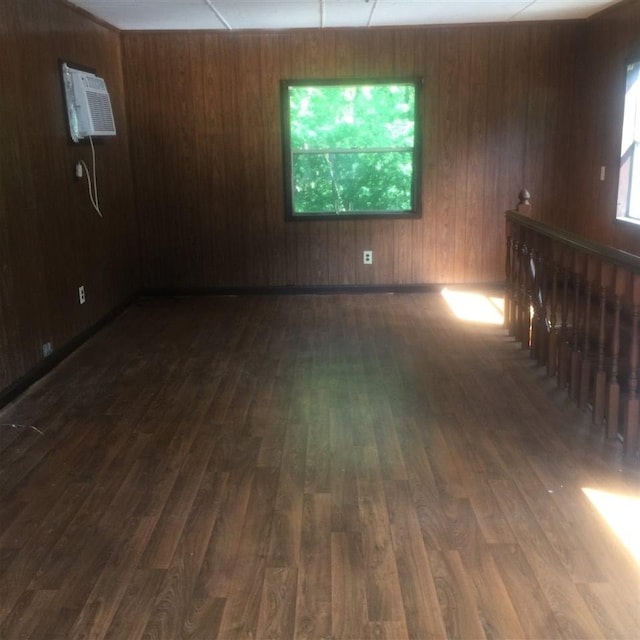 spare room with a wall mounted AC, a wealth of natural light, and dark hardwood / wood-style flooring