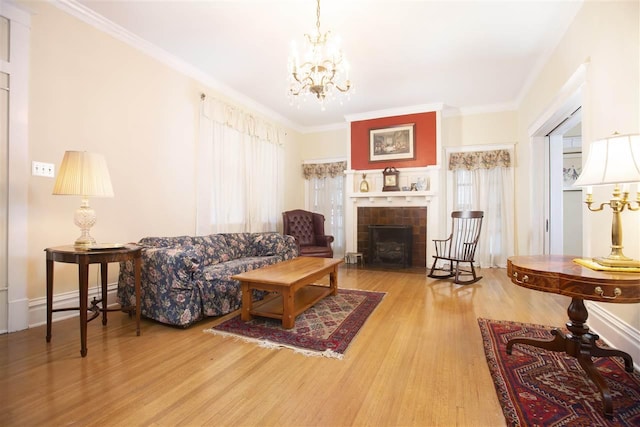 living room featuring a tiled fireplace, a notable chandelier, light wood-type flooring, and plenty of natural light