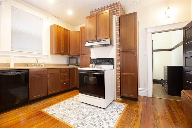 kitchen featuring brick wall, light wood-type flooring, black appliances, and sink