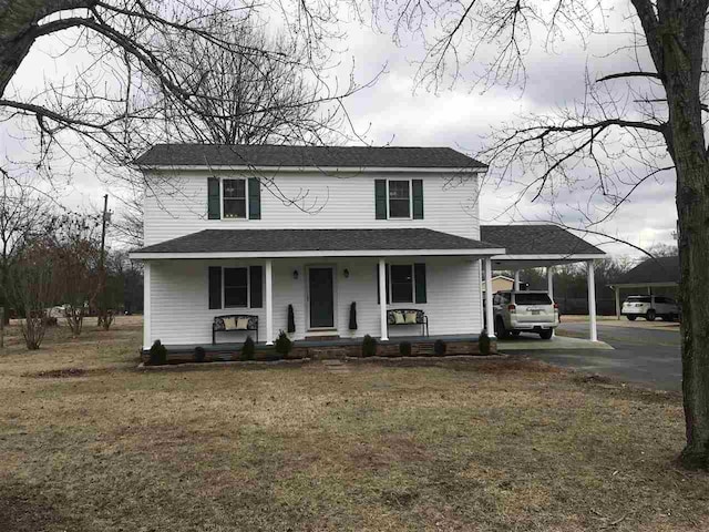 view of front of home with a front yard, a porch, and a carport