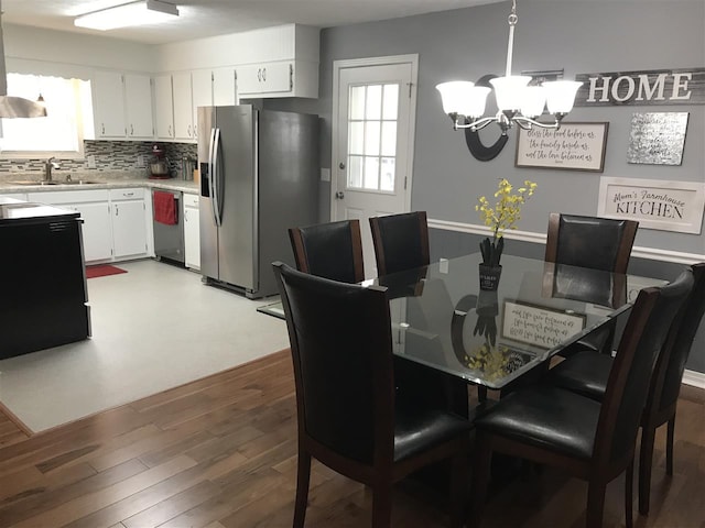 dining space featuring an inviting chandelier, sink, and hardwood / wood-style flooring