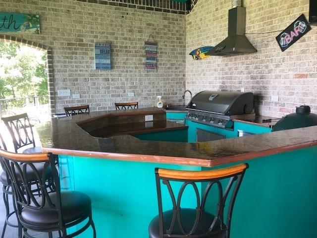 bar featuring wall chimney range hood and brick wall