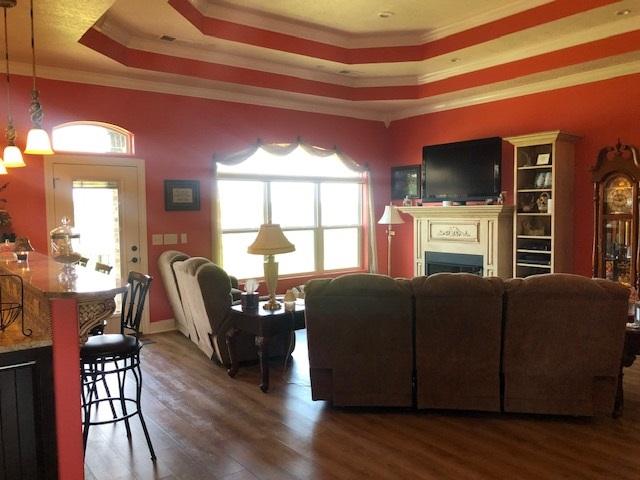 living room with a chandelier, a raised ceiling, dark hardwood / wood-style floors, and crown molding