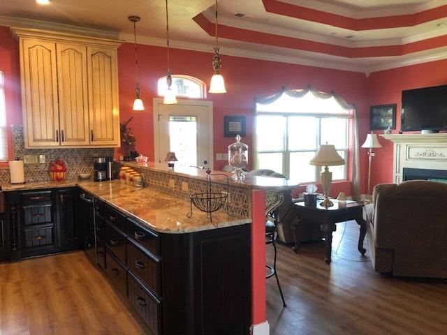 kitchen with a kitchen bar, backsplash, hardwood / wood-style flooring, and crown molding