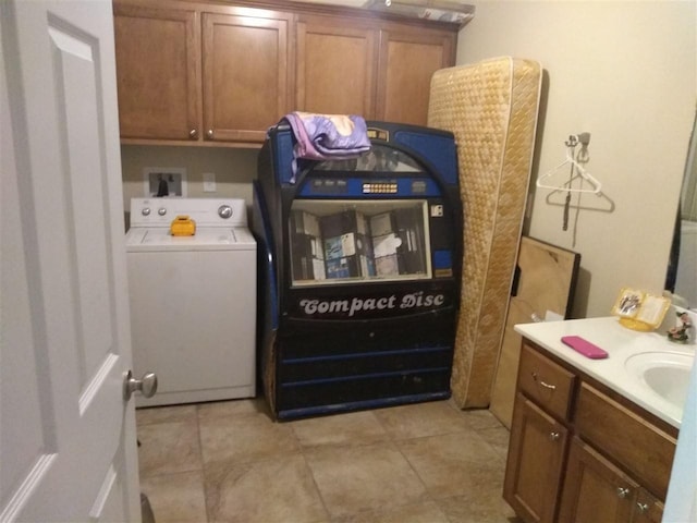 laundry area featuring light tile flooring, sink, cabinets, and washer / dryer