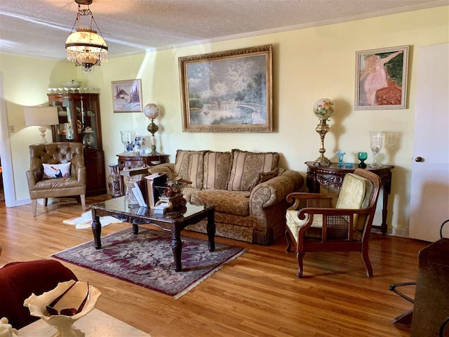 living room featuring a textured ceiling, crown molding, light wood-type flooring, and an inviting chandelier