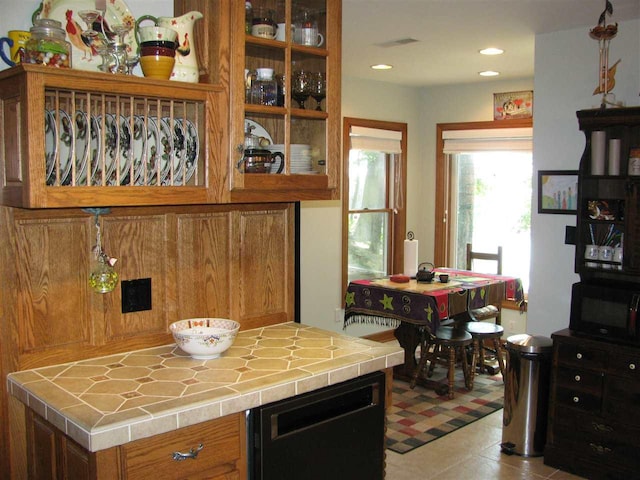 kitchen featuring tile countertops, light tile floors, and black appliances