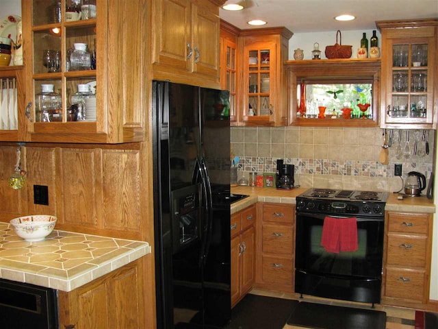 kitchen with tile counters, tasteful backsplash, and black appliances