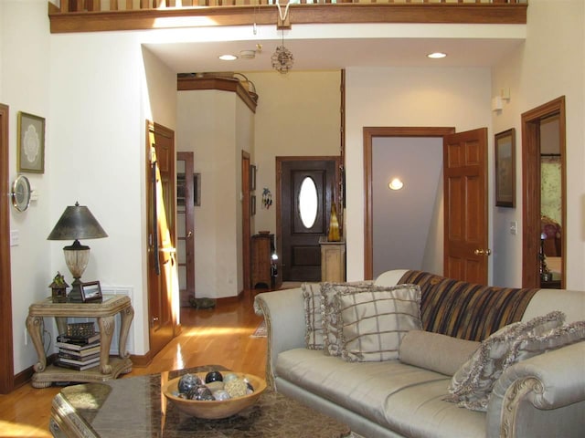 living room with light hardwood / wood-style floors and a towering ceiling