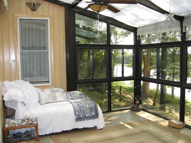 bedroom with a wall of windows, wood walls, and ceiling fan