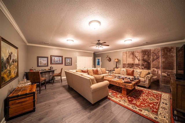 living room featuring ceiling fan, a textured ceiling, ornamental molding, and dark hardwood / wood-style flooring