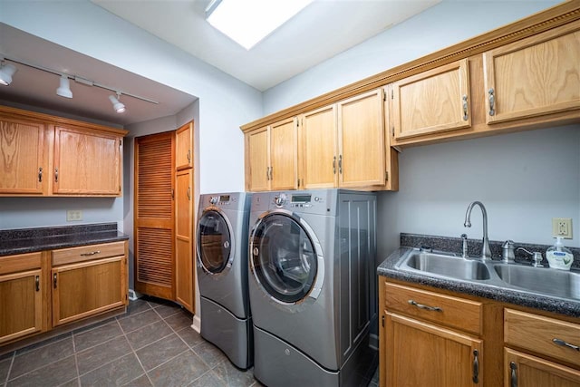 laundry room with dark tile floors, sink, washing machine and clothes dryer, track lighting, and cabinets