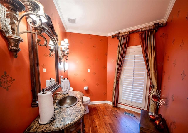 interior space with oversized vanity, toilet, ornamental molding, and wood-type flooring