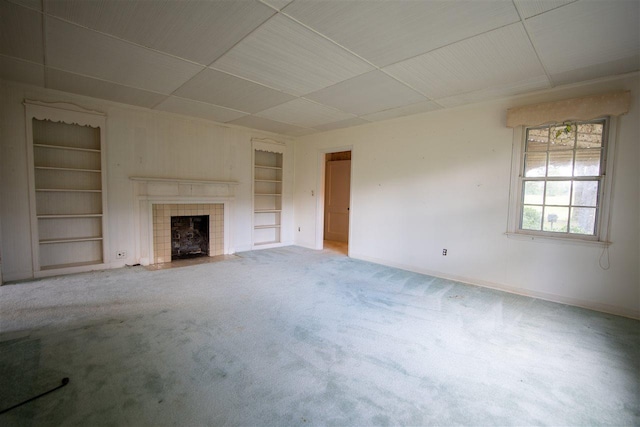 unfurnished living room with built in shelves, light carpet, and a fireplace