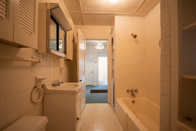 full bathroom featuring tile walls, tile floors, toilet, vanity, and tiled shower / bath