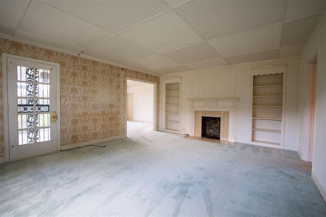 unfurnished living room featuring a fireplace, light colored carpet, and built in shelves