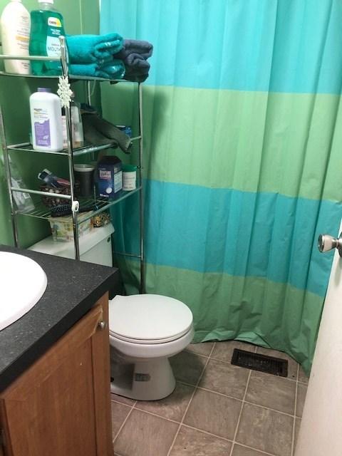 bathroom featuring tile flooring, toilet, and vanity