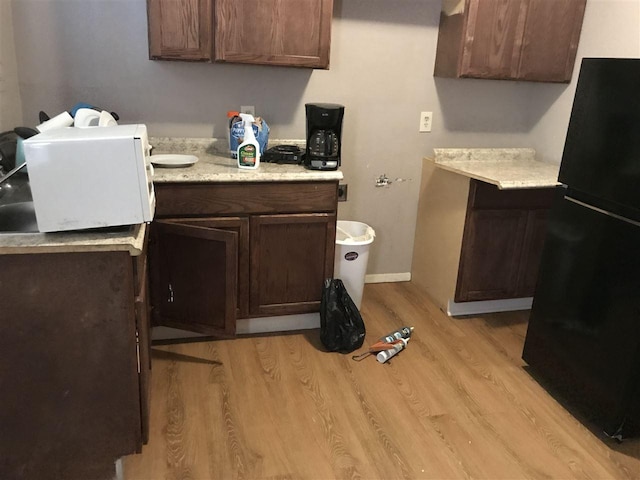 kitchen with black fridge, light wood-type flooring, and dark brown cabinetry