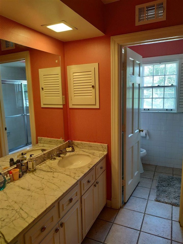 bathroom with tile walls, tile floors, toilet, and vanity