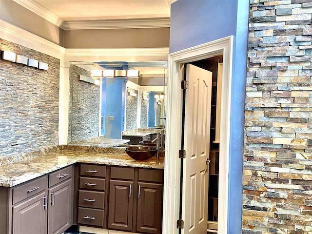 kitchen featuring dark brown cabinets, light stone counters, sink, and ornamental molding