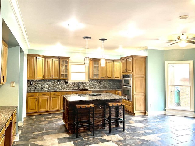 kitchen with sink, ceiling fan, a kitchen island, stainless steel double oven, and backsplash