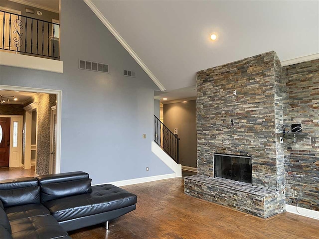 living room with high vaulted ceiling, ornamental molding, a stone fireplace, dark hardwood / wood-style floors, and an inviting chandelier