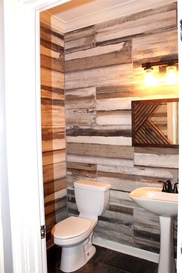 bathroom featuring wood walls, tile flooring, toilet, and ornamental molding