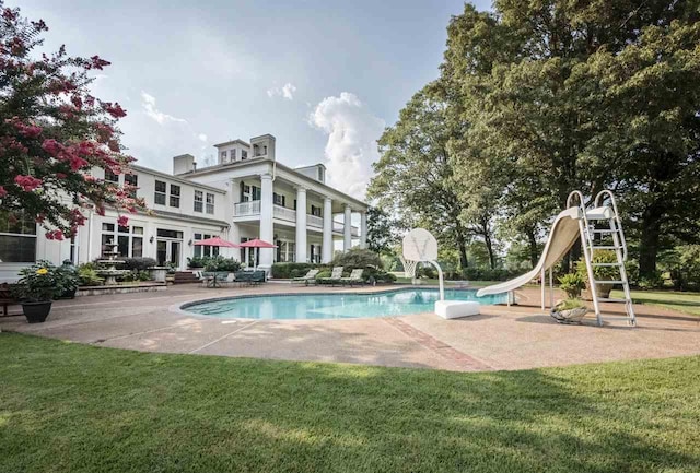 view of swimming pool with a yard and a water slide