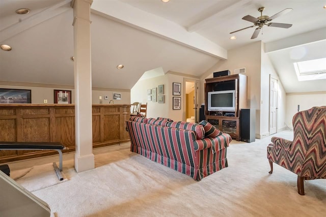 carpeted living room featuring vaulted ceiling with skylight, ceiling fan, and ornate columns