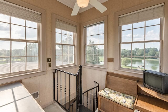 sunroom with a water view and ceiling fan