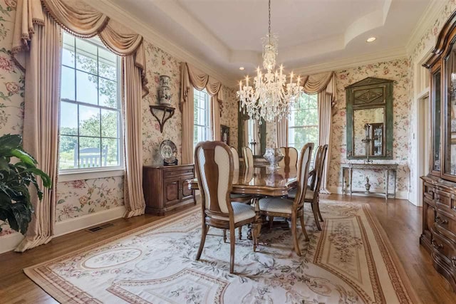 dining area featuring dark hardwood / wood-style flooring, a raised ceiling, ornamental molding, and a chandelier