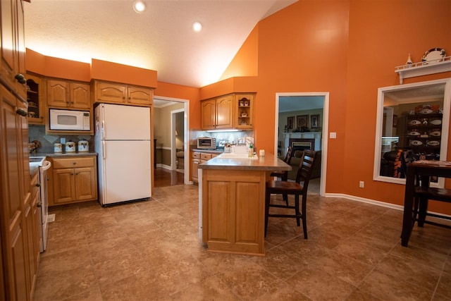 kitchen featuring a breakfast bar, a tiled fireplace, tasteful backsplash, tile flooring, and white appliances