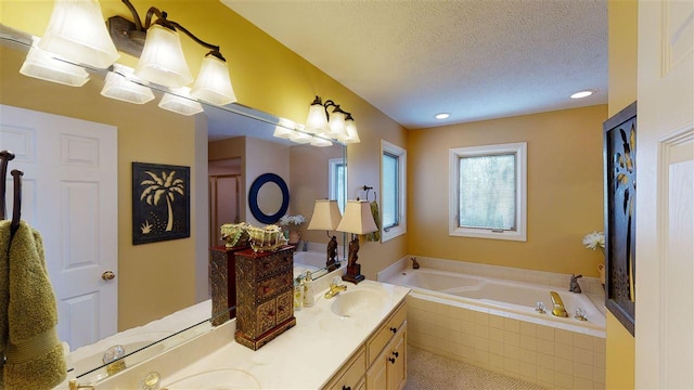 bathroom with dual sinks, tiled bath, oversized vanity, and a textured ceiling