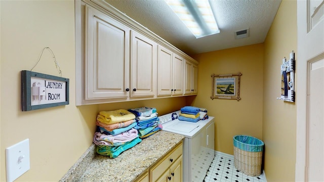 laundry area featuring a textured ceiling, cabinets, light tile flooring, and washer and clothes dryer