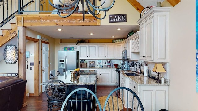 kitchen featuring light stone countertops, white cabinetry, dark wood-type flooring, appliances with stainless steel finishes, and a kitchen island