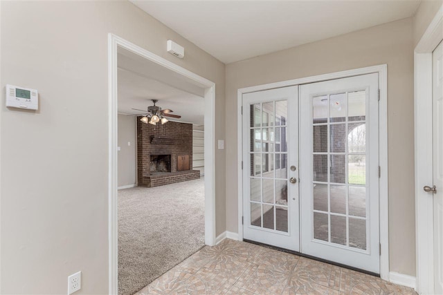 doorway featuring light tile floors, brick wall, a brick fireplace, ceiling fan, and french doors