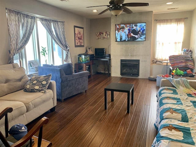 living room featuring ceiling fan, a fireplace, and dark hardwood / wood-style floors