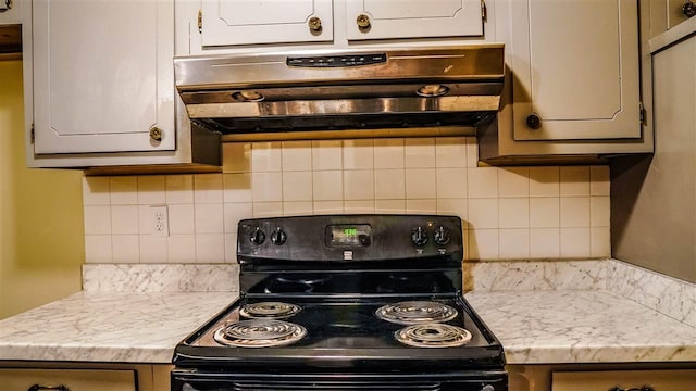 kitchen with light stone counters, tasteful backsplash, black electric range, and custom exhaust hood