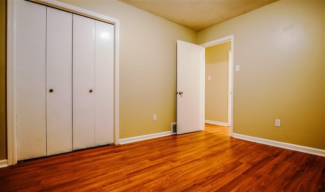 unfurnished bedroom featuring a textured ceiling, a closet, and wood-type flooring