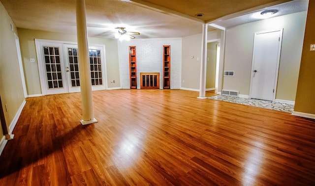 interior space with ornate columns, light wood-type flooring, ceiling fan, a textured ceiling, and french doors