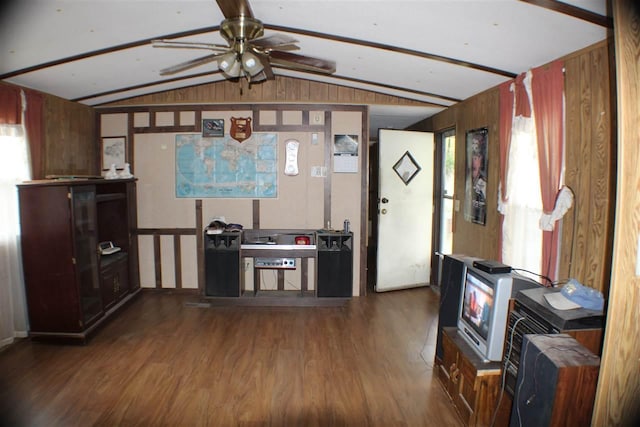 interior space featuring lofted ceiling, wooden walls, dark wood-type flooring, and ceiling fan