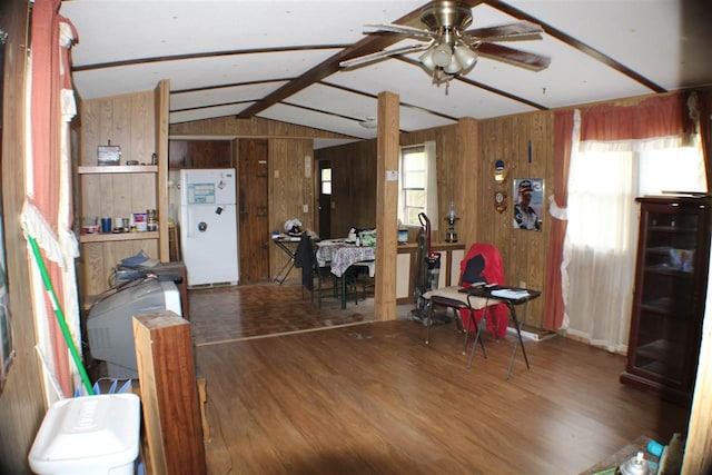 dining area featuring a healthy amount of sunlight, wood walls, dark wood-type flooring, and lofted ceiling